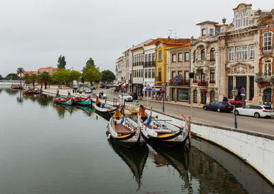 Boats moored in canal by buildings against sky in city