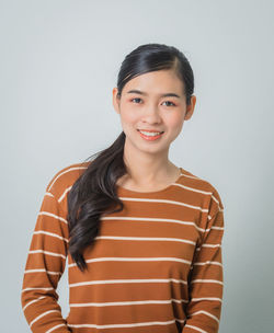 Portrait of smiling woman standing against gray background