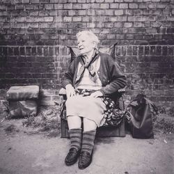 Full length of young woman standing on brick wall