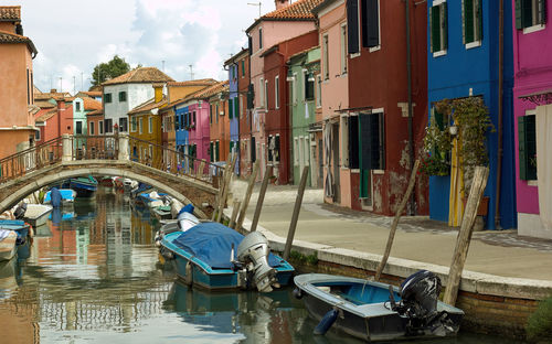 Colorful canal view with boats docked in burano village, venice, italy