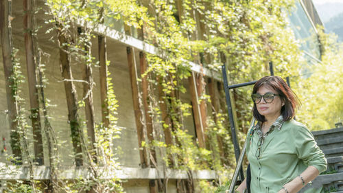 Young woman looking away while standing by plants