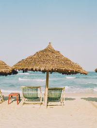 Deck chairs on beach against clear sky