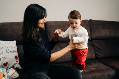 Mother and daughter sitting on sofa at home