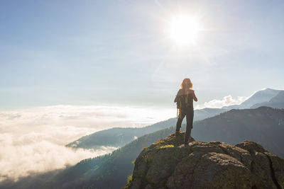 Man standing on rock looking at mountains against sky