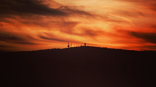 Silhouette landscape against dramatic sky during sunset