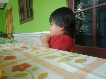 Portrait of girl sitting on table at home