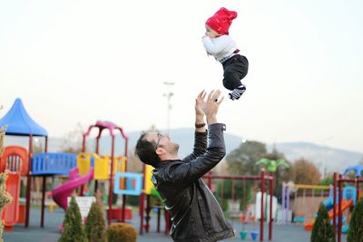 Side view of father tossing son at playground