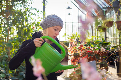 Beautiful woman watering plants in greenhouse