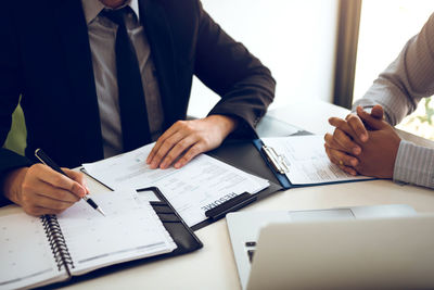 Midsection of man and woman holding paper