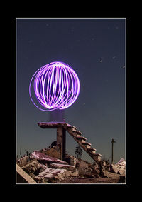 Illuminated ferris wheel against sky at night