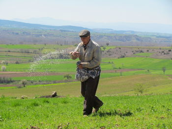 Senior man sprinkling fertilizer on farm