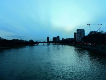 River by buildings against sky at dusk