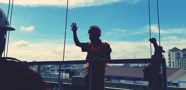 Man photographing against sky in city