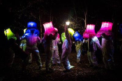 People dancing with lamp shades on head during light festival