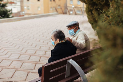 Back view of an unrecognizable elderly couple sitting on a park bench