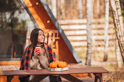 Young woman sitting on bench at table