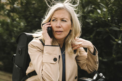 Blond businesswoman contemplating while talking on smart phone