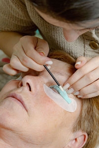 A girl cosmetologist laminates women's eyelashes.