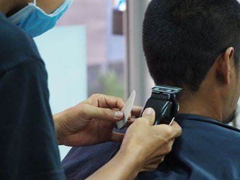 Cropped hands of man cutting customer hair in salon