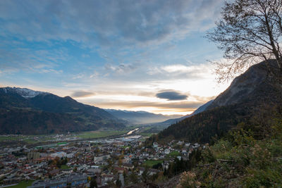 Aerial view of townscape by mountains against sky