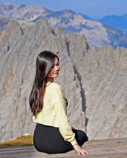 Side view of young woman standing against mountain