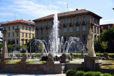 Fountain in city against sky