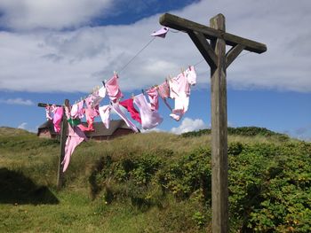 Clothes drying on clothesline at hill against sky