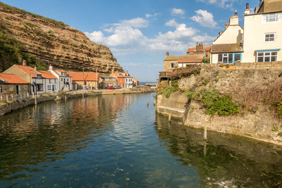 Buildings by river against sky