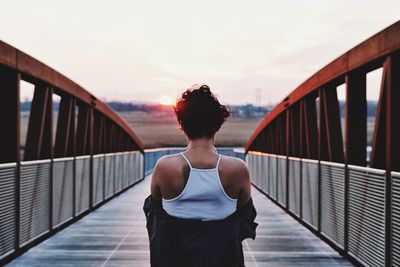 Rear view of woman standing on footbridge