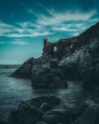 Rock formation on sea shore against sky