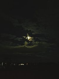 Illuminated street light in city against sky at night