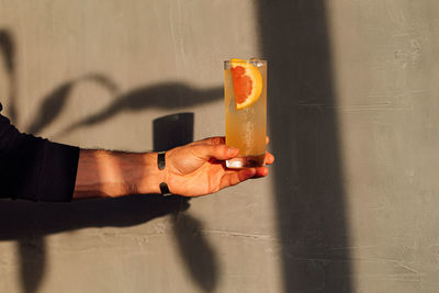 Cropped hand of person holding toy against wall