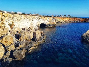 Rock formations in sea against clear blue sky