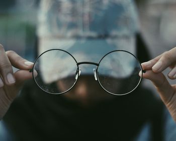 Close-up of hand holding eyeglasses on glass