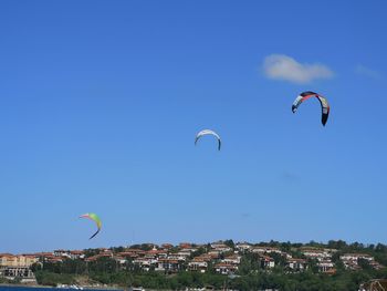 People paragliding against blue sky