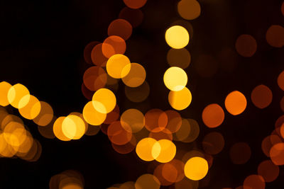 Defocused image of illuminated orange lights at night