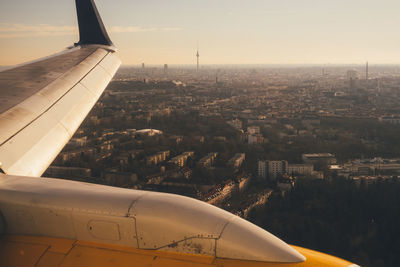 Airplane flying over cityscape against sky