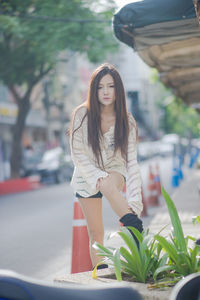 Portrait of beautiful woman standing on footpath in city