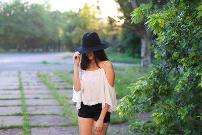 Full length of woman wearing hat standing against trees