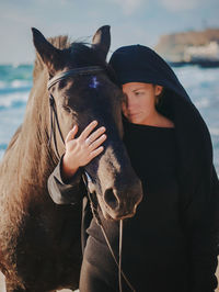 Portrait of young woman with horse standing in water