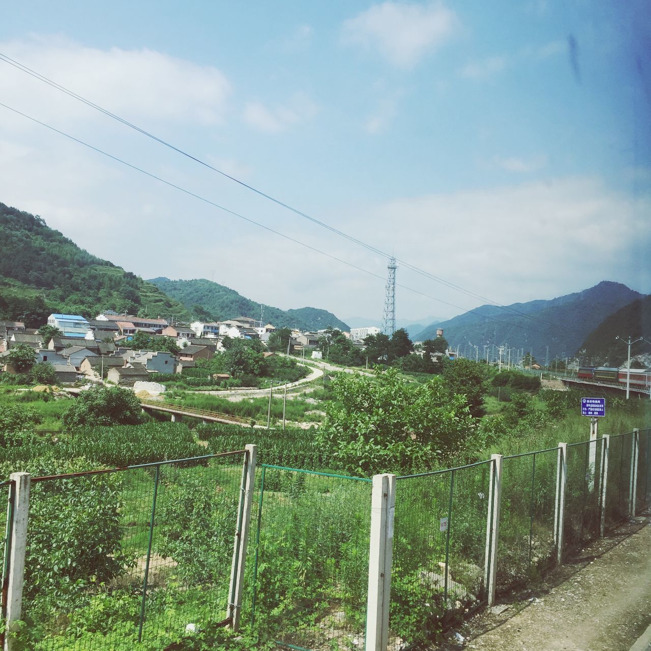 mountain, sky, fence, landscape, mountain range, built structure, nature, cloud - sky, building exterior, field, beauty in nature, architecture, tranquility, tranquil scene, day, plant, electricity pylon, cloud, railing, scenics