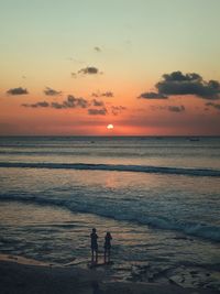 Silhouette people on beach against sky during sunset