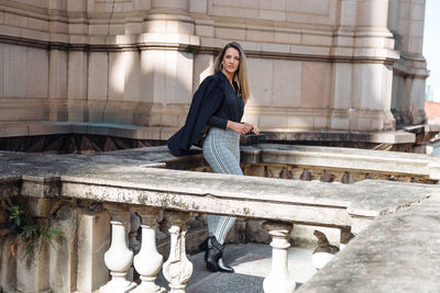 Woman looking away while standing against building