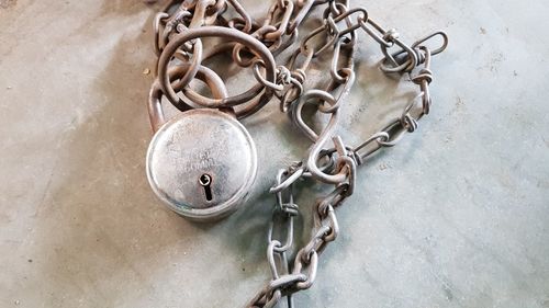 High angle view of padlock with rusty metallic chain on table