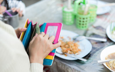 Cropped image of woman removing paper currency from purse at restaurant