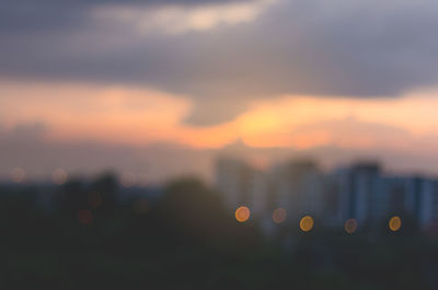 Defocused image of city against sky during sunset