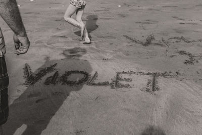 Low section of man with text on sand at beach