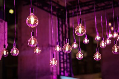 Low angle view of illuminated pendant lights hanging from ceiling