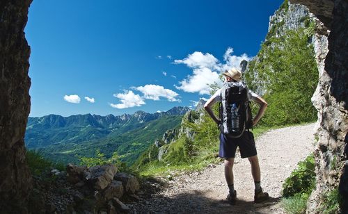 Rear view of man standing on mountain against sky
