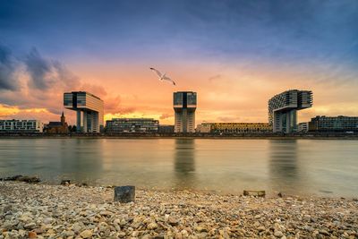 View of river and buildings against sky during sunset